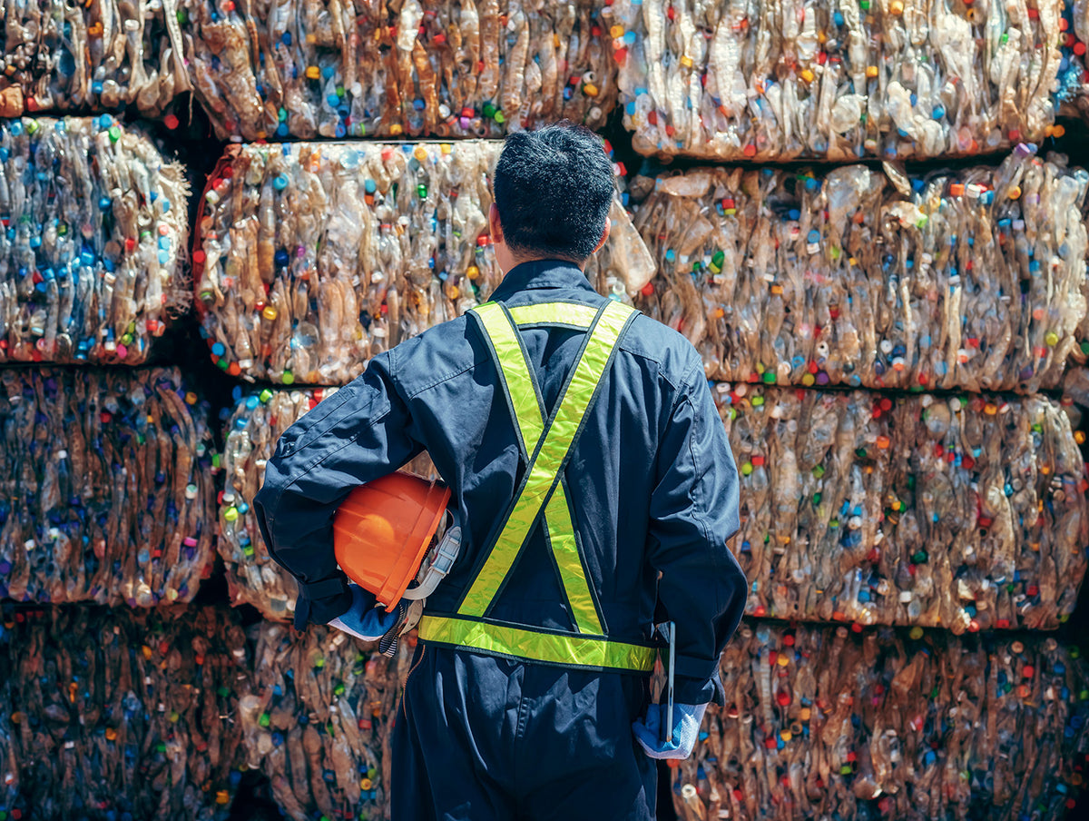 Kunststoff- und Kartonrecyclinganlage mit Mann in Warnweste bei der Vermessung